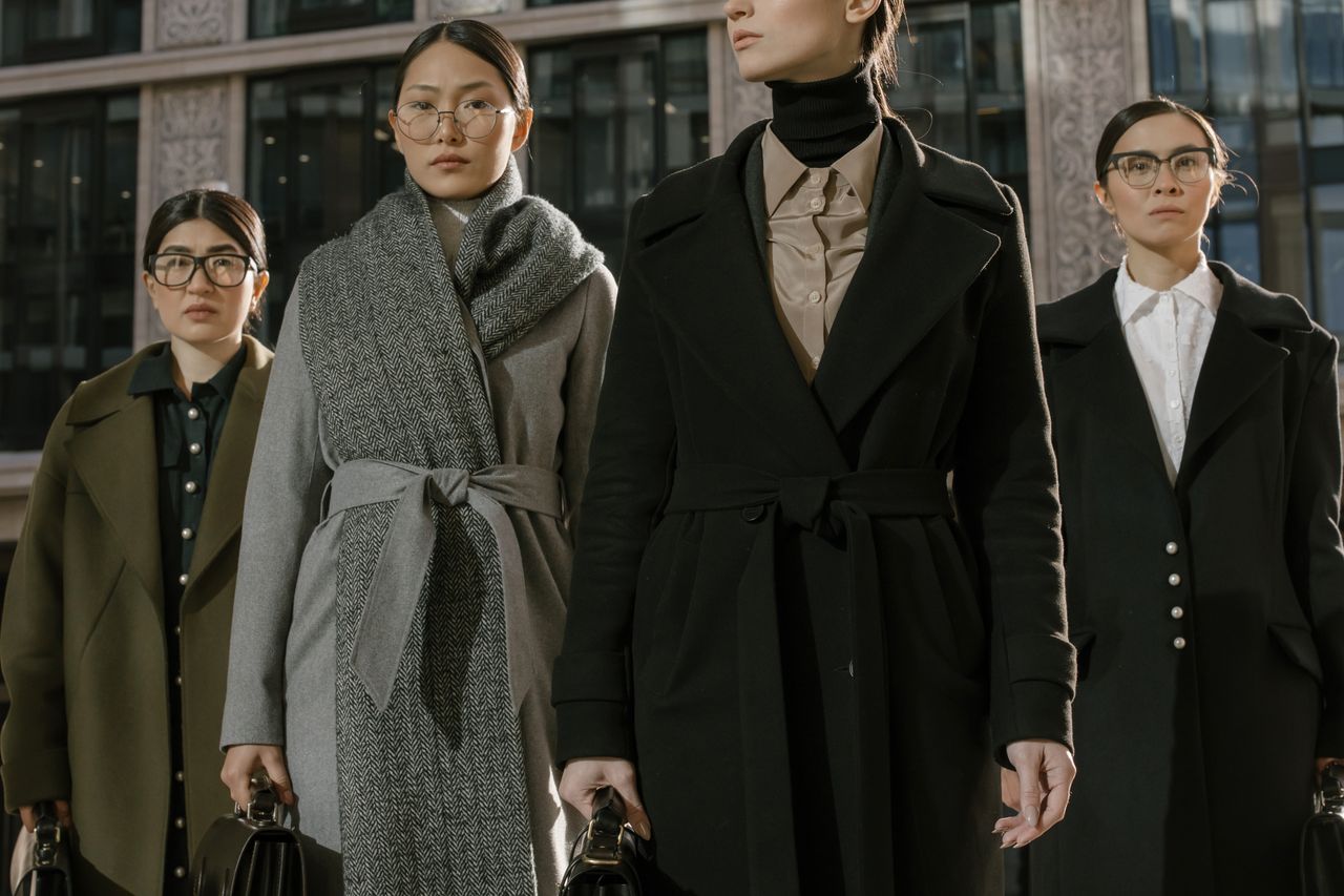 services-01 A group of fashionable women in coats standing confidently in an urban environment.